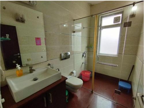 a bathroom with a sink and a toilet and a window at Whiite Panda - Backpacker Hostel in Delhi Greater Kailash in New Delhi