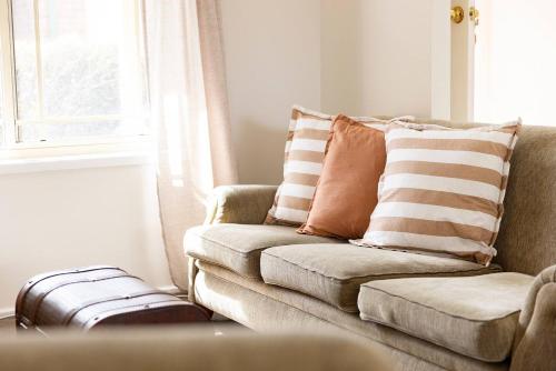 a living room with a couch and a suitcase at Ingall Hearth - Cosy Comfort near Newcastle Beach in Mayfield