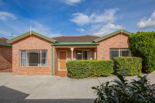 a brick house with bushes in front of it at Ingall Hearth - Cosy Comfort near Newcastle Beach in Mayfield