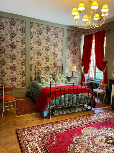 a bedroom with a bed with red sheets and floral wallpaper at Domaine Les Bruyères in Autry-le-Châtel