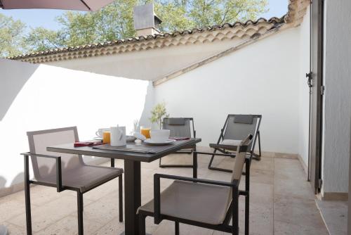 a table and four chairs on a patio at Hôtel & Restaurant de charme - La Bégude Saint-Pierre in Vers Pont du Gard