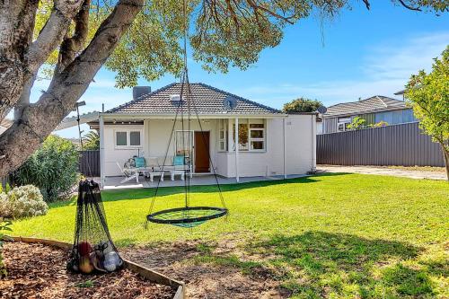 a yard with a swing in front of a house at Christies Grove - Seaside Bliss near McLaren Vale in Christies Beach