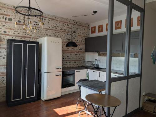 Il comprend une cuisine équipée d'un réfrigérateur, d'une table et de chaises. dans l'établissement Charming 2-bedroom, near city center, à Toulouse