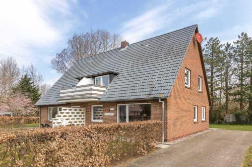 une maison en briques rouges avec un toit à la mansarde dans l'établissement Linke Haushaelfte ID 906, à Sankt Peter-Ording