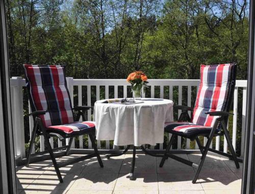 dos sillas y una mesa con un jarrón de flores en un porche en Wohnung OG rechts Achtern Diek ID 083, en Sankt Peter-Ording