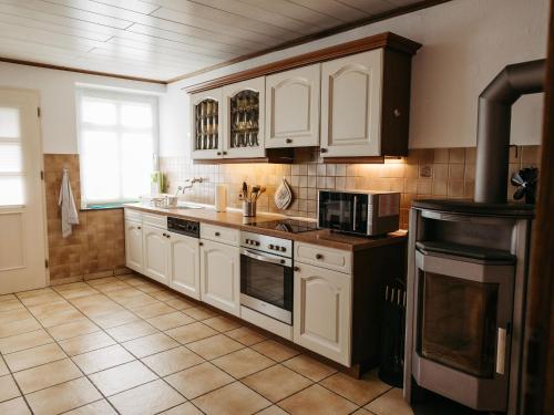 a kitchen with white cabinets and a stove top oven at Ferienwohnung Wennetal in Schmallenberg