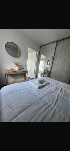 a bedroom with a large white bed with a large mirror at La tour carree, t2 avec parking in Cité de Port-Neuf