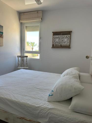 a white bed with a pillow and a window at La Savina Ses Platgetes in La Savina