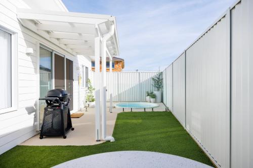 a white pergola on a patio with a table and grass at Olas Villa 6 - Plunge Pool & Walk to Beach in Anna Bay