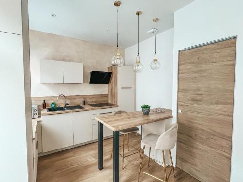 a kitchen with a wooden table and white cabinets at T2 centre ville de Perros Guirec in Perros-Guirec