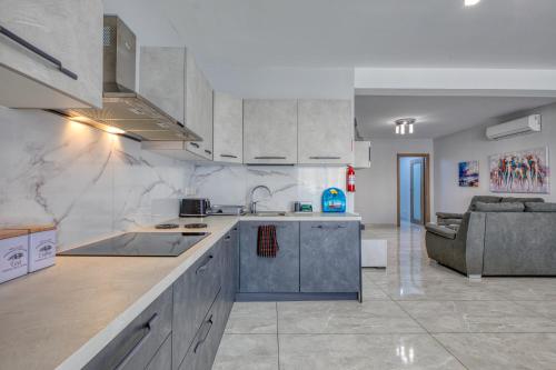 a kitchen with white cabinets and a couch in a room at Luxury Central Malta Apartment Brand New by SF Homes in Qormi
