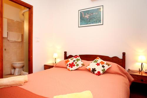 a bedroom with a bed with orange sheets and pillows at Rooms & Studio Stipcic in Trogir