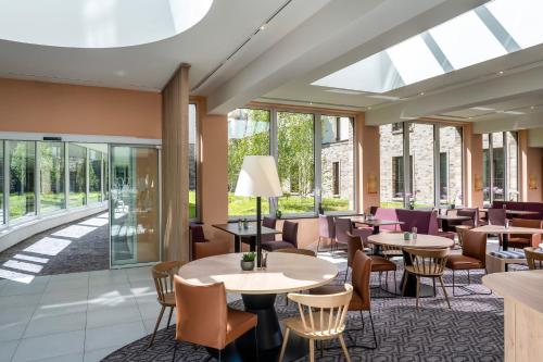 a restaurant with tables and chairs and windows at Hampton By Hilton Potsdam Babelsberg in Potsdam
