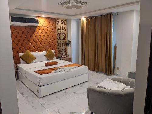 a bedroom with a large white bed and two chairs at Nuva Hotel in Islamabad