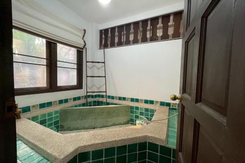 a bathroom with a tub with green tile at The Royal Shilton Resort in Chiang Mai