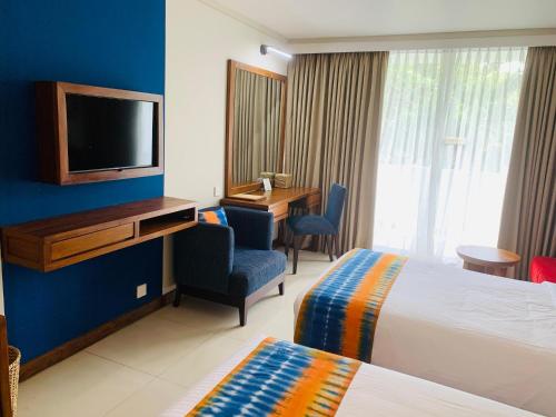 a hotel room with a bed and a tv on a wall at Pegasus Reef - A Beach Resort in Colombo in Colombo