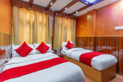 two beds in a room with red and white pillows at OYO 830 Hotel Amrit Kunja in Kathmandu