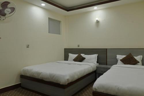 two beds in a room with white walls at OYO 828 Hotel White Dreams Palace in Kathmandu