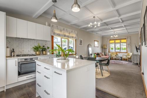 a kitchen with white cabinets and a living room at Point Chevalier Life in Auckland