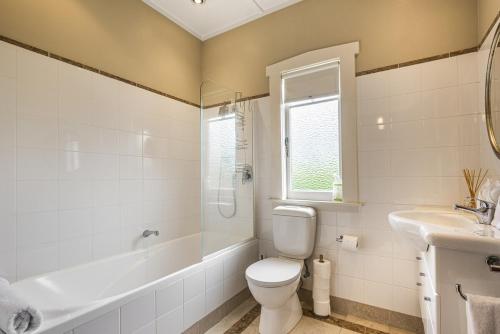 a bathroom with a toilet and a tub and a sink at Point Chevalier Life in Auckland