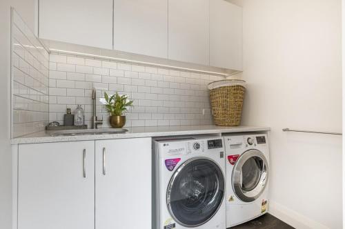 a white kitchen with a washing machine and a sink at Point Chevalier Life in Auckland