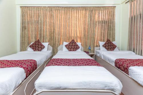 three beds sitting in a room with curtains at OYO 831 Hotel Mission Inn Pvt Ltd in Kathmandu
