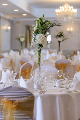 a room with white tables with white flowers in a vase at Clybaun Hotel in Galway