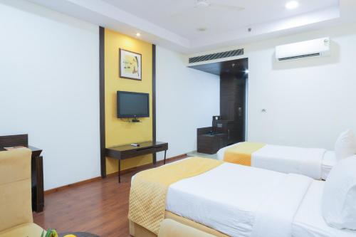 a hotel room with two beds and a television at Hyphen Premier-Business Hotel in Meerut