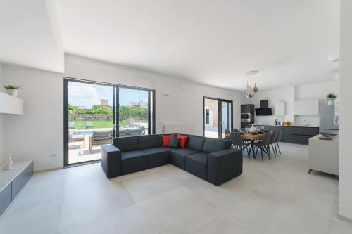 Una sala de estar con un sofá negro y una cocina. en Villa Nara Luxury - Private Pool - 16 guest, en Tricase