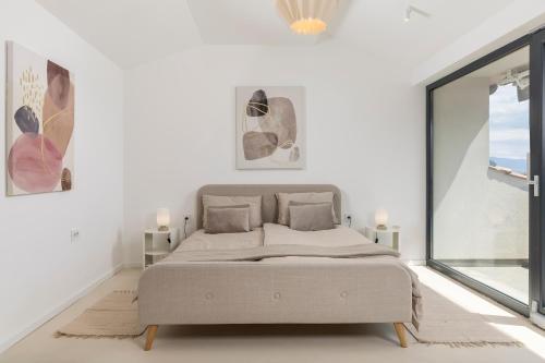 a bed in a white room with a large window at Villa Carla house with hot tub and beautiful garden in Ičići