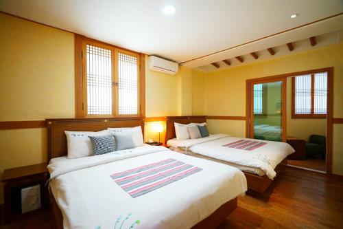 two beds in a room with two windows at Gamyoungroo Hanok Hotel in Jeonju
