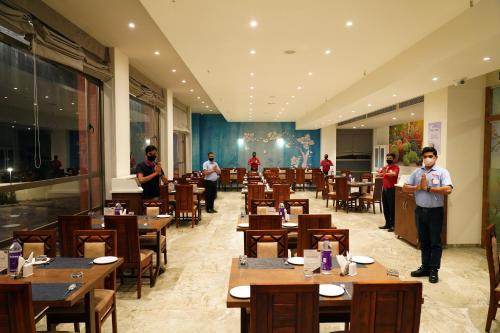 a restaurant with tables and people standing in a room at VITS The Somnath Gateway in Somnath