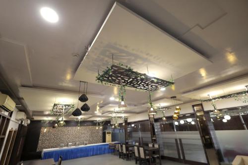 a dining room with a table and chairs and lights at Hotel Shagun, Piplod City Centre Surat in Surat