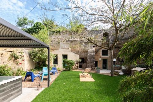 un jardin avec des chaises bleues et une maison dans l'établissement La Petite Perrière Gite, à Doué-la-Fontaine