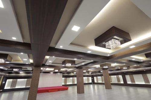 a large room with columns and a ceiling with a chandelier at Hotel Shagun, Piplod City Centre Surat in Surat