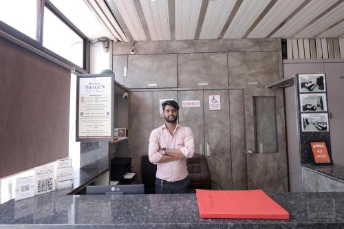 a man standing in an office with his arms crossed at Hotel Shagun, Piplod City Centre Surat in Surat