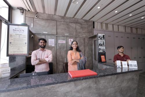 a group of three people standing at a counter at Hotel Shagun, Piplod City Centre Surat in Surat