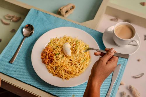 a person eating a plate of noodles and a cup of coffee at Artisan By Sebu in Galle