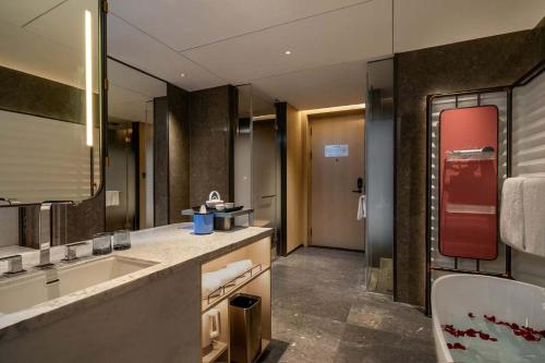 Un baño con lavabo y un espejo grande. en 上海虹桥荷逸唐酒店北新泾地铁站Shanghai Hongqiao Heyitang Hotel Beixinjing Subway Station Branch, en Shanghái