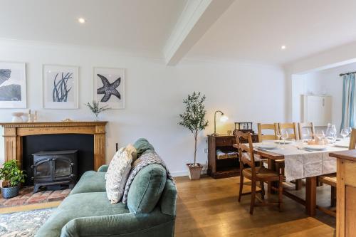 a living room with a green couch and a dining table at Warblers - West Wittering in Chichester