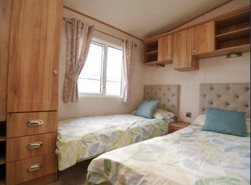 a bedroom with two beds and a window at Seaview Caravan, Perran Sands in Perranporth