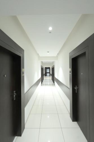 an empty hallway with two doors and a white tile floor at Hotel Shagun, Piplod City Centre Surat in Surat