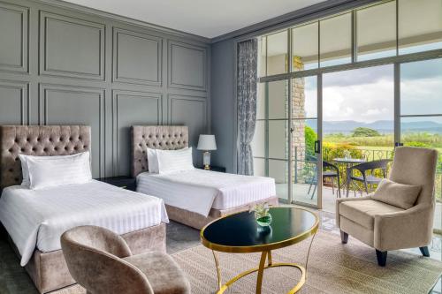 a hotel room with two beds and a table and chairs at Mövenpick Resort Khao Yai in Ban Wang Sai