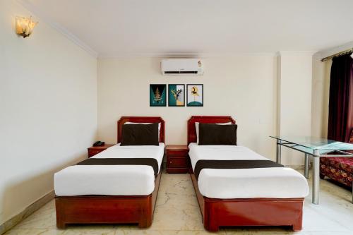 two beds in a room with a table at Super Townhouse Civil Aviation HAL Road in Bengaluru