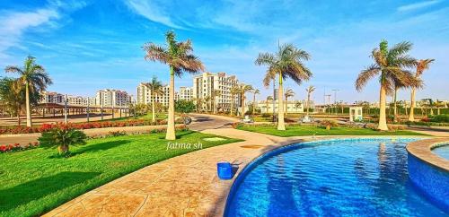 einen Pool in einem Park mit Palmen in der Unterkunft Apartment 160 m for rent, CELIA Compound TMG, direct on the green river, New Administration Capital in Madīnat al Amal