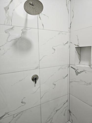 a shower with white marble walls and a shower head at Star Room's in Durrës