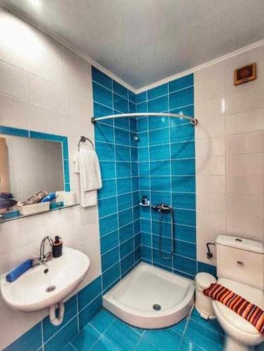 a blue tiled bathroom with a sink and a toilet at Rena's Rooms Μελίντα in Melínta