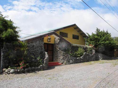 una casa gialla con un muro di pietra di El Refugio La Brisa del Diablo a Valle Hornito