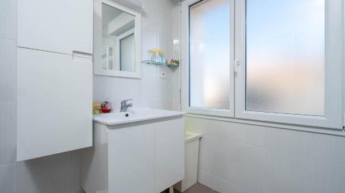 une salle de bain blanche avec un lavabo et une fenêtre dans l'établissement Les Magnarelles - 2P4, au Grau-du-Roi