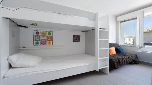 Ce lit superposé blanc se trouve dans un dortoir doté d'un canapé. dans l'établissement Les Magnarelles - 2P4, au Grau-du-Roi